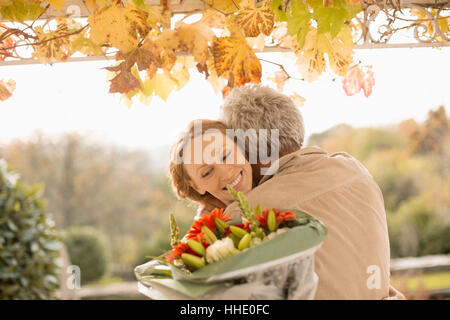 Ehemann überraschend Frau mit Blumenstrauß auf Herbst Terrasse Stockfoto