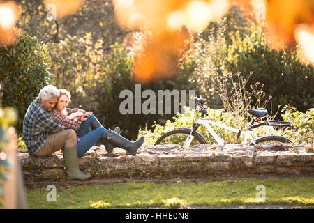 Zärtlich umarmt auf Steinmauer im Herbst Park paar Stockfoto