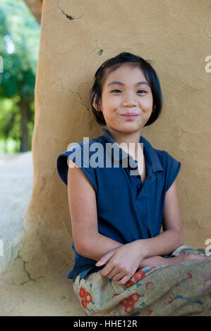 Eine Mädchen aus Rangamati sitzt vor ihrem Schlamm Mauern umgebene Haus in der Nähe Kaptai See, Chittagong Hill Tracts, Bangladesch Stockfoto