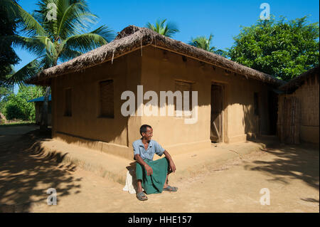 Ein Mann sitzt vor seinem Haus in den Chittagong Hill Tracts, Bangladesch Stockfoto