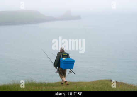 Ein Fischer zu Fuß in Richtung Worms Head von Rhossili Bucht auf The Gower in Süd-Wales, UK Stockfoto