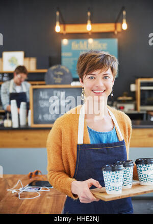 Porträt-zuversichtlich weibliche Café-Besitzer halten Tablett mit Kaffeetassen Stockfoto