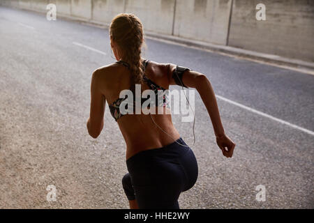 Fit weibliche Läufer in BH und MP3-Player Sportarmband läuft auf städtischen Straße Stockfoto