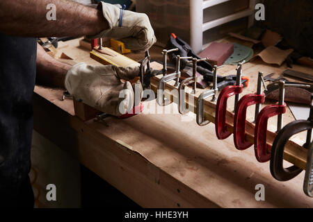 Bogenmacher arbeitet an einem Holzbogen in seiner Werkstatt Befestigungsklammern auf das Holz. Stockfoto