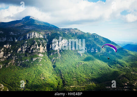 Ein Gleitschirm im Flug über ein Tal in den Bergen. Stockfoto