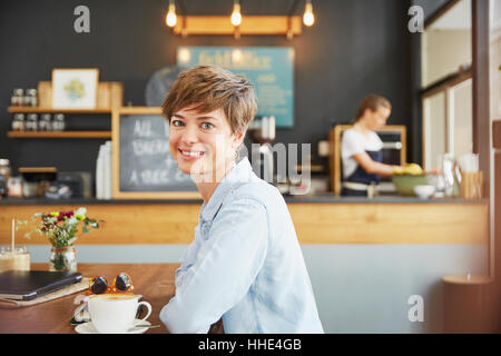 Porträt lächelnde Frau trinkt Kaffee am Café-Tisch Stockfoto