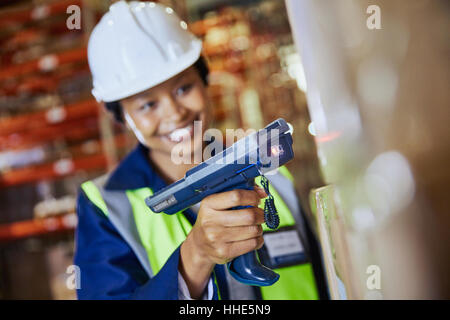 Lächelnd Arbeitnehmerin mit Scanner Scannen Karton im Auslieferungslager Stockfoto