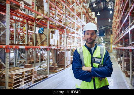 Porträt zuversichtlich Arbeiter mit verschränkten im Auslieferungslager Stockfoto