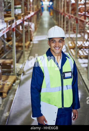 Porträt lächelnde Arbeiter mit Zwischenablage in Verteilung Lager Gang Stockfoto