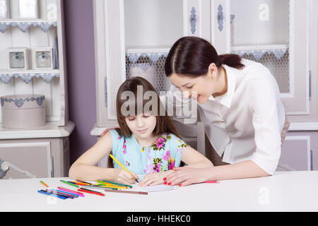 Glückliche schöne Mutter Lehren ihrer Tochter zu malen, malen und lächelnd und Blick in die Kamera. Studio gedreht. Stockfoto