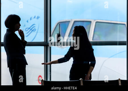 Silhouettenbestand Bild von 2 Flughafenangestellten, die im Hintergrund mit einem Flugzeug diskutieren. Stockfoto