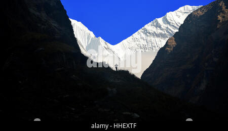 Ein Trekker Silhouette gegen den Schnee bedeckt Berg von Ganggapurna in den Modi Khola-Tal Annapurna Sanctuary, Stockfoto