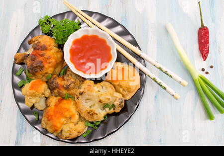 paniert Gebratener Blumenkohl mit Stäbchen und Ketchup auf einem Teller Stockfoto