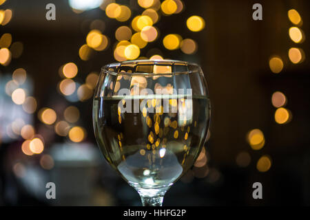 Ein Glas Pinot Grigio weißen Wein mit funkelnden Lichter im Hintergrund Stockfoto