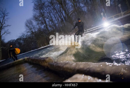 Eisbach River, Deutschland. 18. Januar 2017. Ein Mann surft auf die Welle mit seinem Surfbrett im Schnee und Temperaturen weit unter dem Gefrierpunkt am Eisbach River im englischen Garten der Nacht vom 18. bis 19. Januar 2017. Der Eisbach stehende Welle in der Prinzregenten-Strasse ist ein beliebter Ort bei Surfern das ganze Jahr über. Bildnachweis: Dpa picture Alliance/Alamy Live News Stockfoto