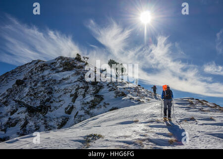 Wanderer auf Schneeschuhen unterwegs für einen verschneiten Berggipfel in den französischen Pyrenäen am sonnigen Wintertag. Stockfoto