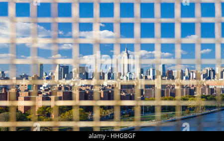 NYC Panorama Skyline Innenstadt Wolkenkratzer gesehen durch die Gitterstäbe des Zaunes auf der Williamsburg Bridge zwischen Brooklyn und Manhattan in New York City Stockfoto