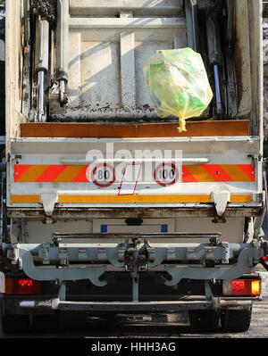 große städtische Hygiene LKW während der Sammlung von festen Abfällen in der Metropole und einer großen gelben Tasche mit Müll Stockfoto