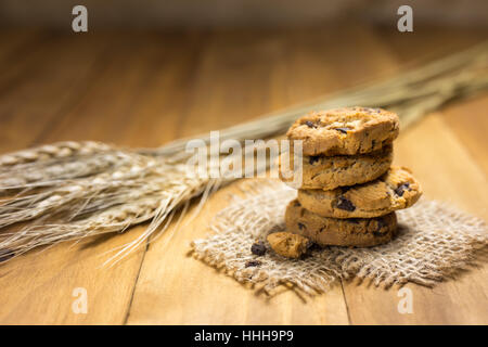 Schokoladen-Plätzchen auf meschotschek Tuch auf Holz. Chocolate Chip Cookies und Reis Malz erschossen auf einem braunen Tuch. Stockfoto