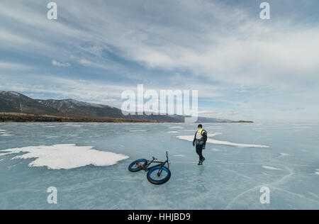 Fatbike auch als fat-Bike oder Fett-Reifen Fahrrad - Radfahren auf großen Rädern. Radfahrer geht auf seinem Fahrrad auf dem zugefrorenen See. Stockfoto