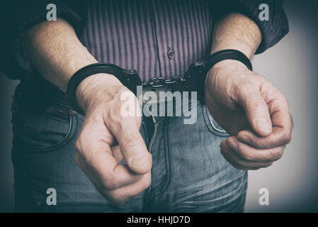 männliche Hände mit Handschellen gefesselt Nahaufnahme. Kriminalität-Konzept Stockfoto