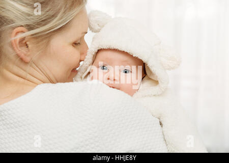 glückliche Mutter mit Säugling Babymädchen in weißen flauschigen Kostüm gekleidet Stockfoto