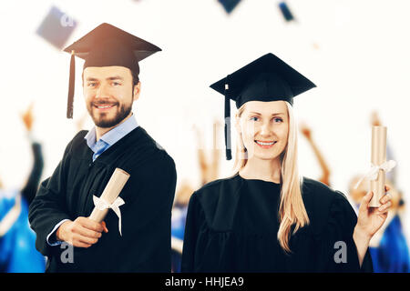 glücklich Absolventen mit einem Diplom tragen Kleider bei Abschlussfeier Stockfoto