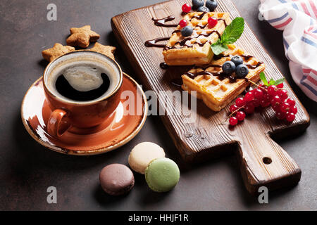 Süßigkeiten, Kaffee und Waffeln mit Beeren auf Schneidebrett Stockfoto