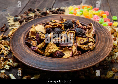 Getrocknete Früchte (Äpfel, Birnen, Aprikosen), Beeren, Rosinen und Nüssen in einer Schüssel auf dunklem Holz. Nahaufnahme Stockfoto