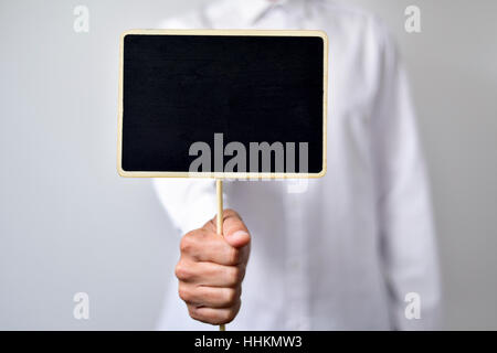 ein junger kaukasischer Mann trägt ein weißes Hemd zeigt eine leere schwarze Schild mit einem Textfreiraum Stockfoto