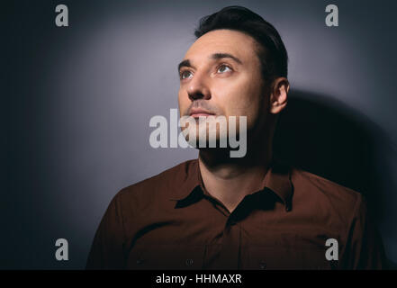 Porträt von ein gut aussehender Mann blickte auf grauem Hintergrund Stockfoto
