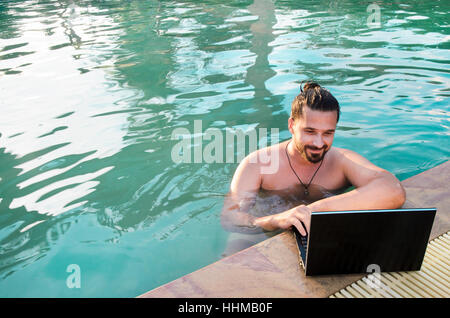 Arbeit am Laptop vom Schwimmbad Stockfoto