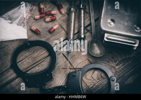 Harte Drogen und Handschellen auf Holztisch Stockfoto