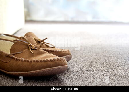 Generische Mens Wildleder Mokassin Hausschuhe auf Teppich neben Sofa in ein schönes Wohnzimmer. Platz für Text zu kopieren. Stockfoto