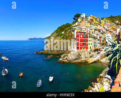 Riomaggiore Dorf auf Klippe Felsen, Boote und Meer bei Sonnenuntergang, Seelandschaft in Cinque Terre Nationalpark Cinque Terre, Ligurien Italien Europa. Stockfoto