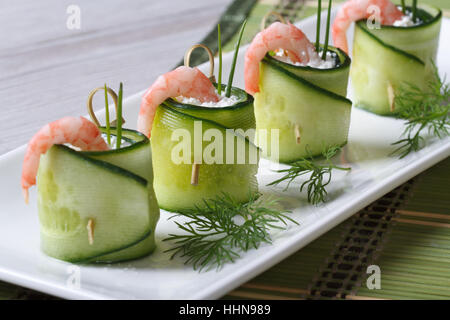 Vorspeise von Gurken Rollen mit Garnelen und Frischkäse Closeup auf einem weißen Teller. horizontale Stockfoto