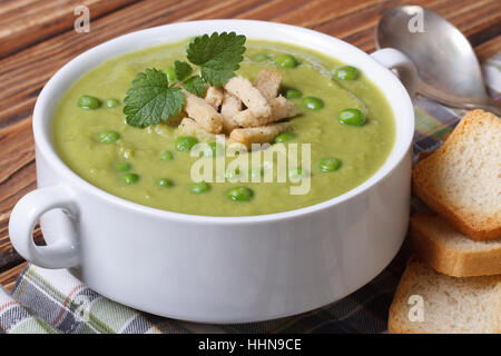 Grüne Erbsensuppe mit Croutons und Minze Closeup auf einem Holztisch. horizontale Stockfoto
