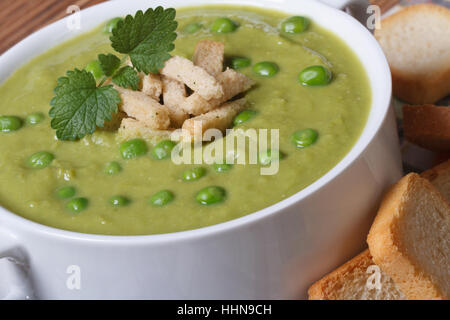 Cremesuppe mit grünen Erbsen mit Croutons Closeup auf einem Holztisch. horizontale Stockfoto