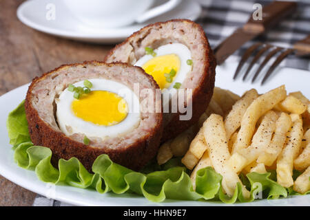 von Scotch Ei und Bratkartoffeln Nahaufnahme auf einem Teller auf den Tisch. horizontale Stockfoto