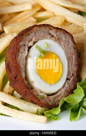 von Scotch Egg mit Pommes Frites und Salat auf einem Teller-Makro. vertikale Stockfoto