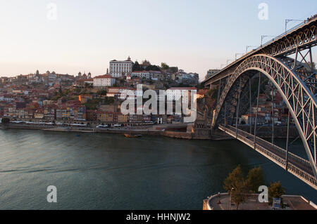 Portugal: Boote bei Sonnenuntergang und die Skyline von Porto mit Blick auf die Luiz I, die Doppel-gedeckten Metall Bogenbrücke über den Fluss Douro Stockfoto