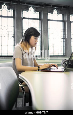Chinesische Frau sitzt in der Bibliothek mit laptop Stockfoto