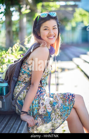 Porträt von lächelnden Chinesin auf Bank tragen Rucksack Stockfoto