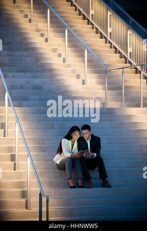 Paar sitzt auf der Treppe SMS auf dem Handy Stockfoto