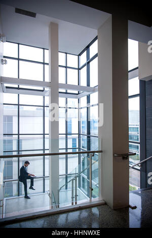 Hispano-Amerikaner Geschäftsmann sitzt auf der Treppe Geländer in der Nähe von Fenster Stockfoto