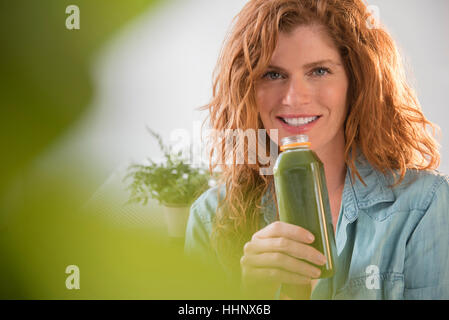 Lächelnde kaukasischen Frau trinken grünen smoothie Stockfoto