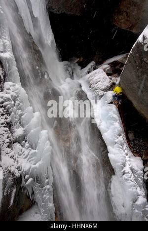 Fotograf vom Klettern Fixseile am Rand teilweise gefrorenen Wasserfalls sichern sich im Ort um Eiskletterer fotografieren suspendiert Stockfoto