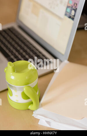 Sippy Tasse in der Nähe von Dateiordner und laptop Stockfoto