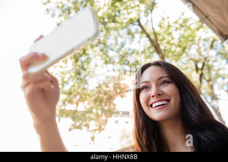 Thai Frau posiert für Handy Selfie lächelnd Stockfoto