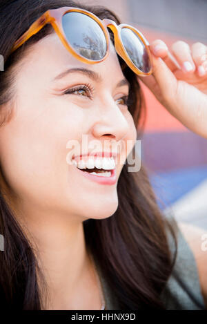 Thai Frau heben Sonnenbrille lächelnd Stockfoto
